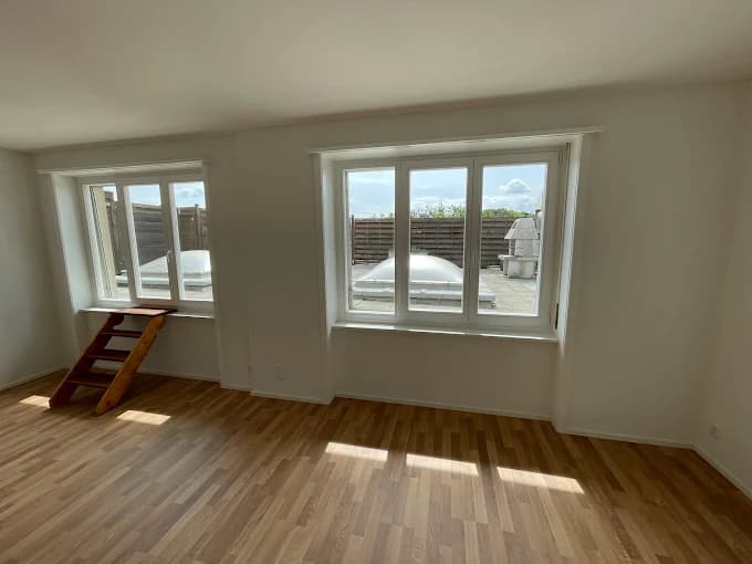 Pièce claire avec parquet et deux fenêtres blanches à plusieurs vantaux