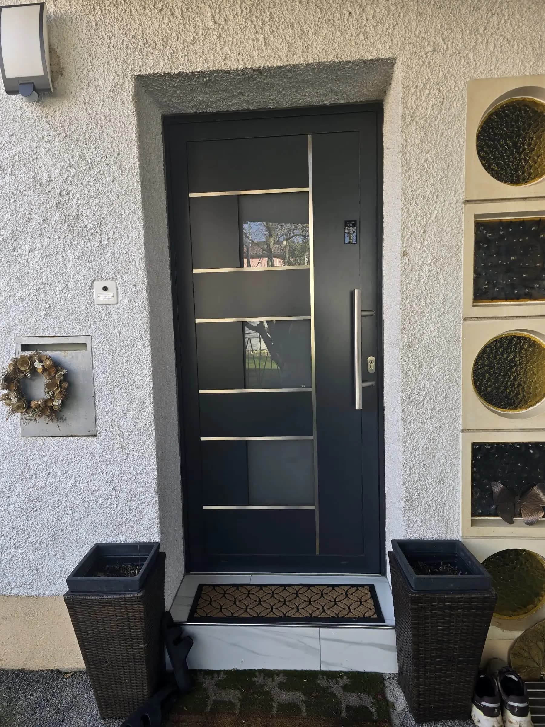 Black entrance door with glazed inserts and a vertical handle