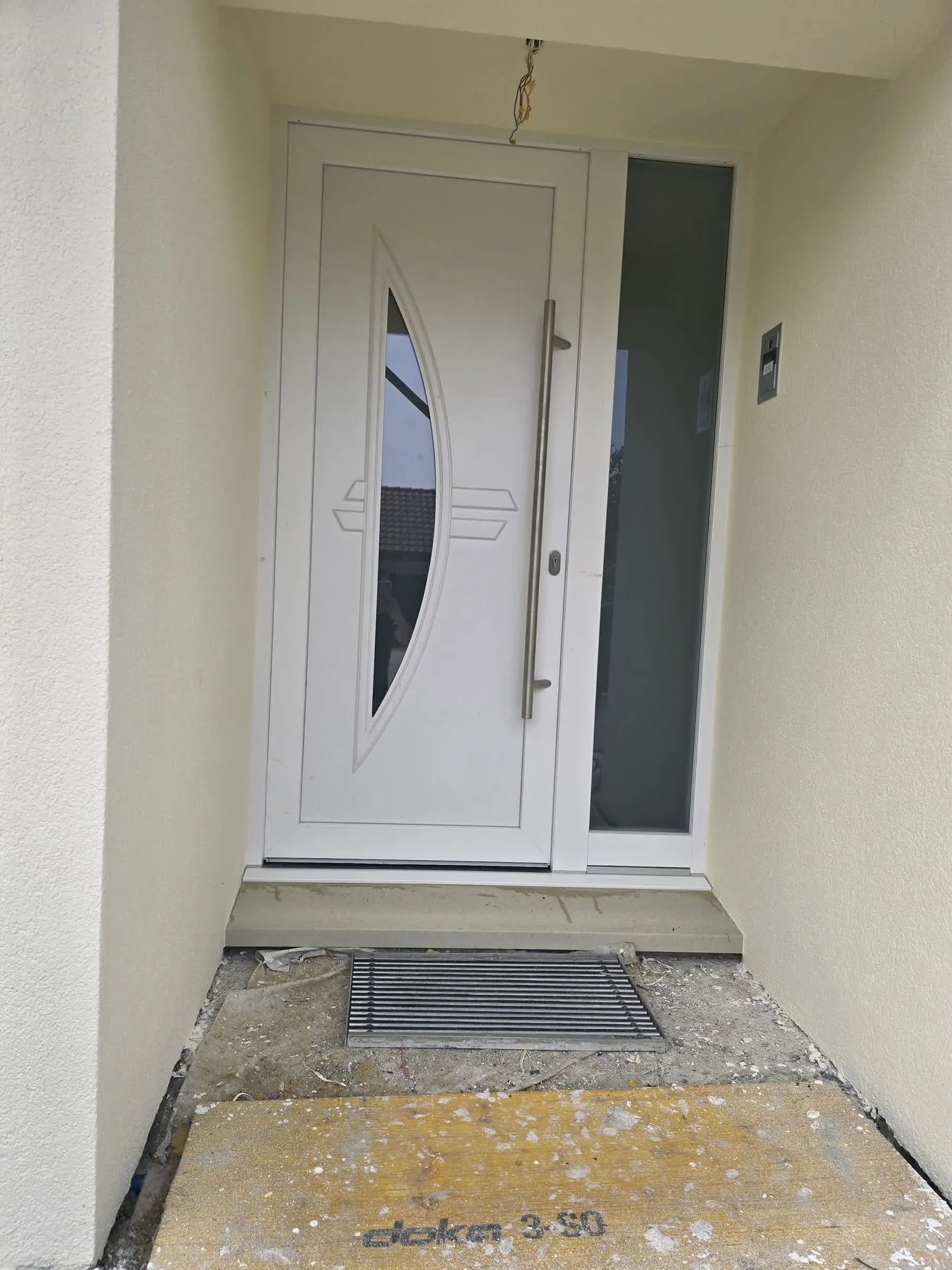 Weisse Haustür mit verglastem Oberlicht während der Montage